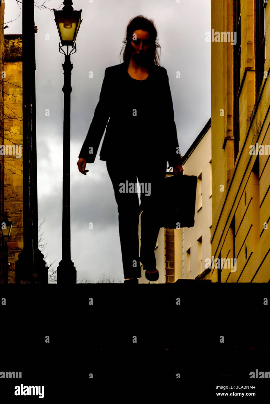 Une femme en costume descend un escalier, portant une mallette. Banque D'Images