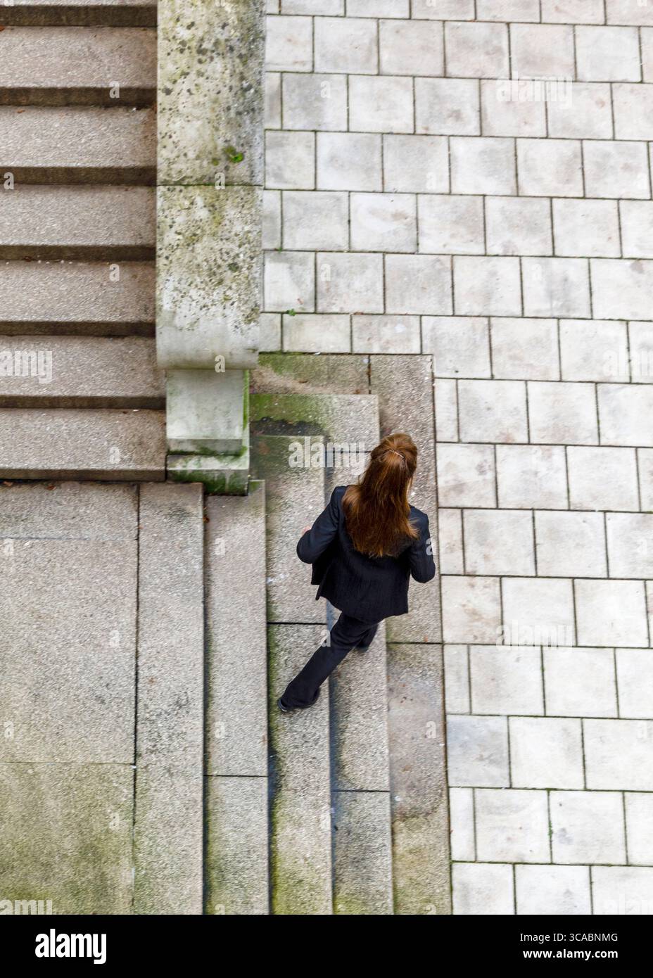 Une femme en costume noir descend un escalier. Banque D'Images