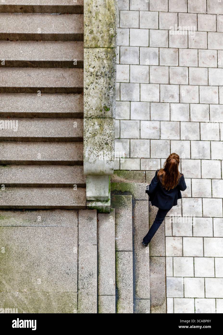 Une femme en costume noir descend un escalier. Banque D'Images