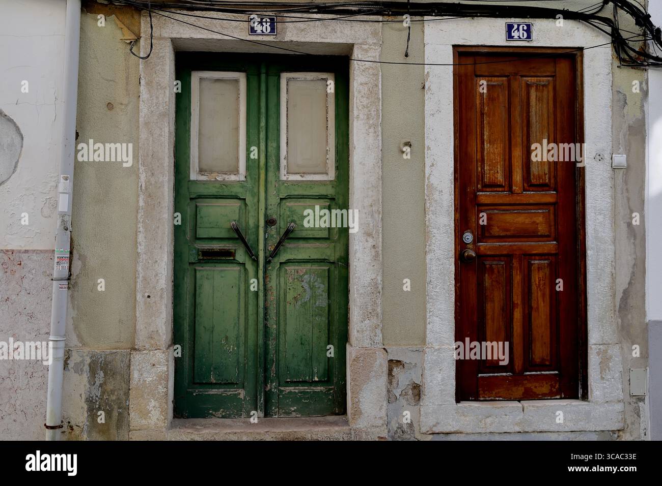 Portes en bois vert et brun vieilli dans des cadres en pierre sur une façade historique à Almada, Lisbonne, une scène de rue pour le voyage et les éditoriaux culturels. Banque D'Images