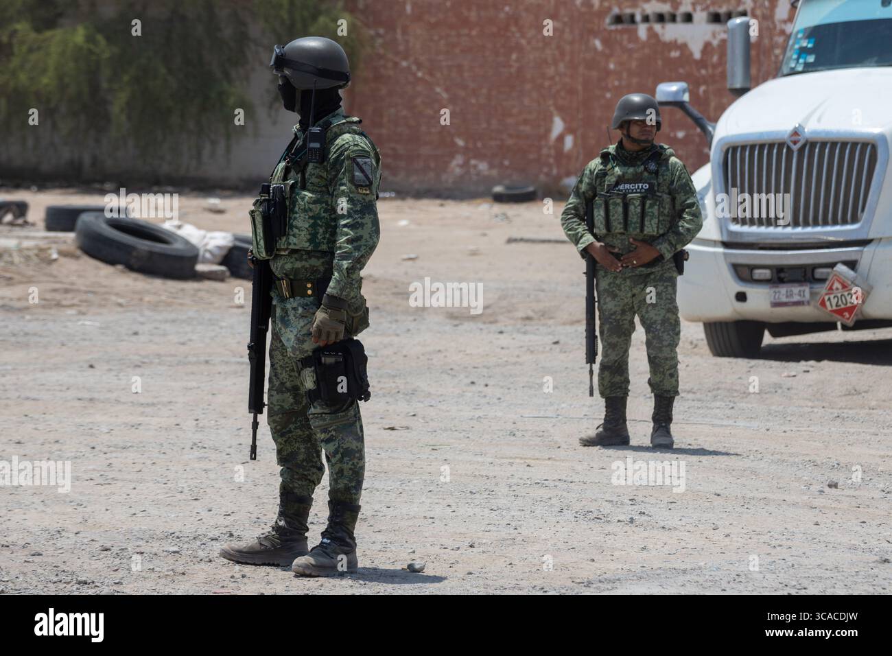 Deux soldats patrouillent dans une rue poussiéreuse de Ciudad Juarez au milieu de l'escalade de la violence urbaine. Banque D'Images