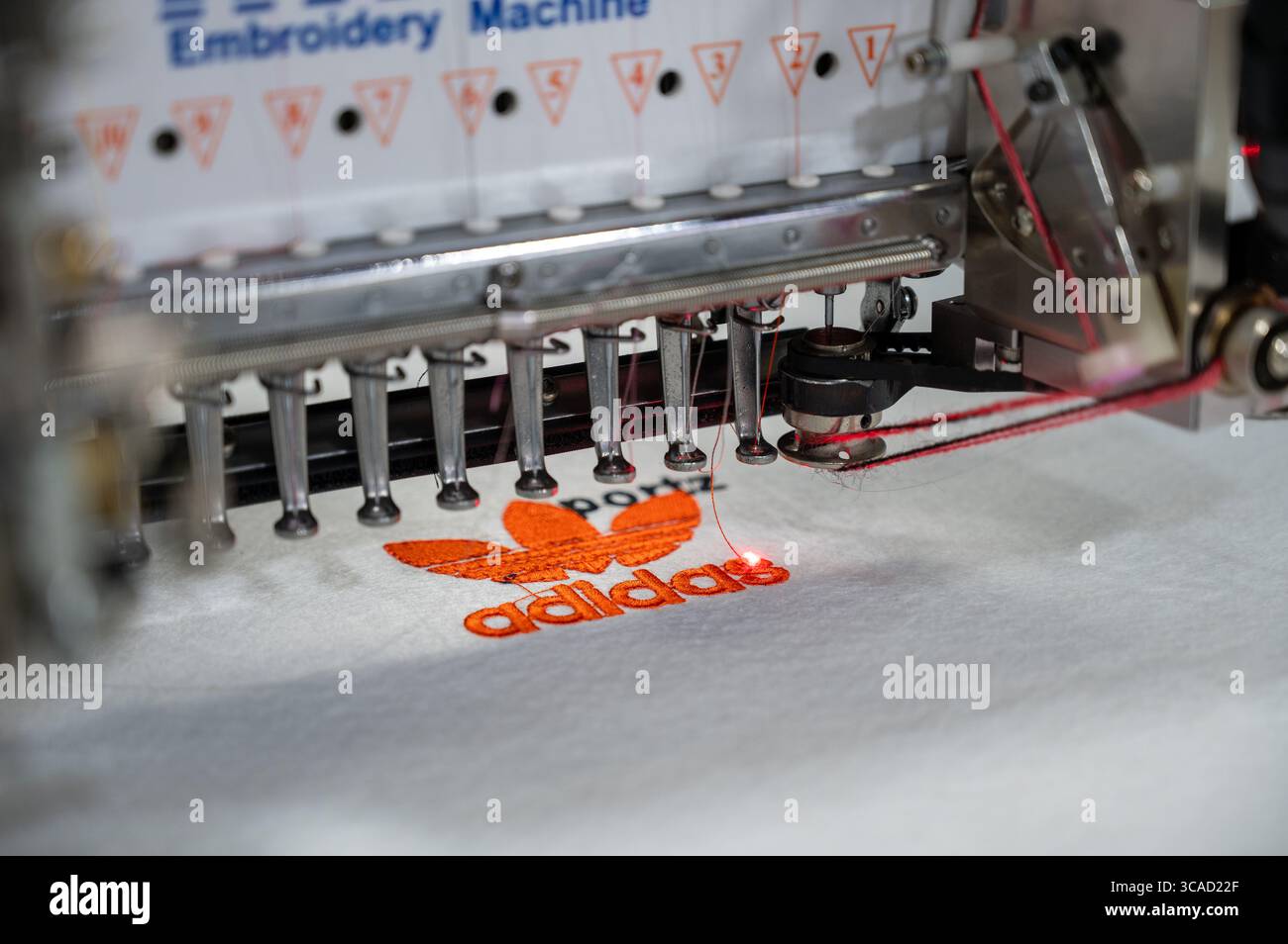 Une machine à broder automatique fabriquée en Chine coud un logo Adidas sur le tissu de la chaussure lors de la 9ème foire internationale de la chaussure en Inde, qui s'est tenue à Bharat Mandapam. ITPO (India Trade promotion Organisation) organise la 9ème édition de la Foire internationale de la chaussure en Inde (IIFF) du 6 au 8 août 2025, à Bharat Mandapam. Il s'agit d'une exposition B2B (Business-to-Business), présentant une large gamme de produits, y compris des chaussures, des matériaux synthétiques, des composants de chaussures, des accessoires, des machines et des équipements, et produits chimiques. Environ 250 exposants participent à la foire. Banque D'Images