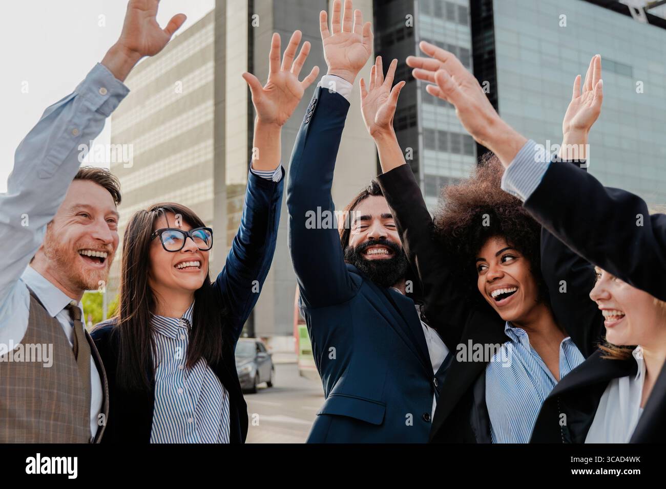 Heureuse équipe d'affaires diversifiée célébrant le succès en plein air dans la ville Banque D'Images