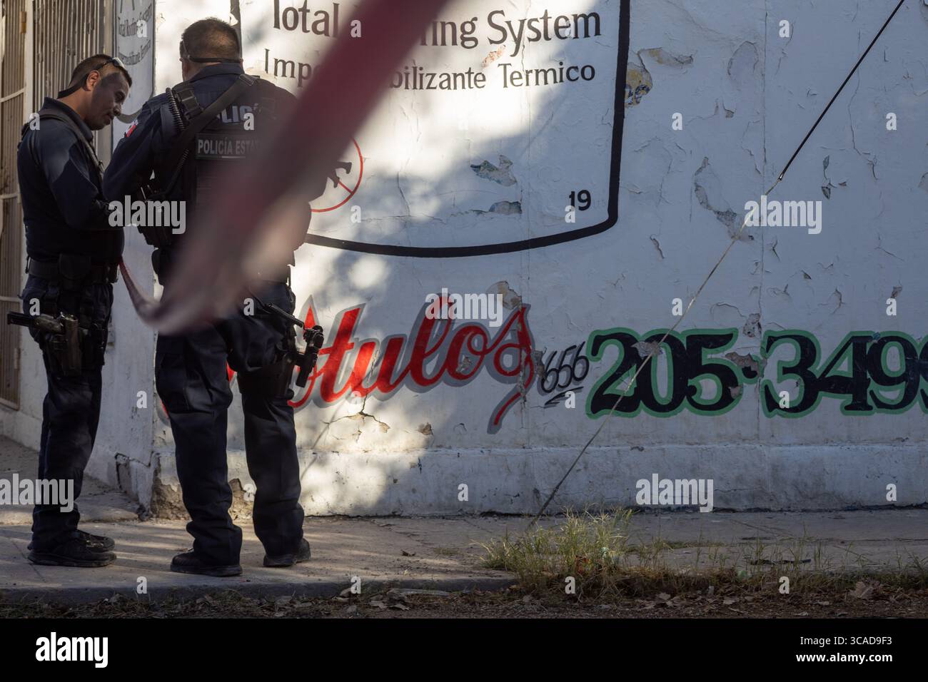 Deux officiers discutent des stratégies de lutte contre la violence urbaine à Ciudad Juarez, gravée de graffitis. Banque D'Images
