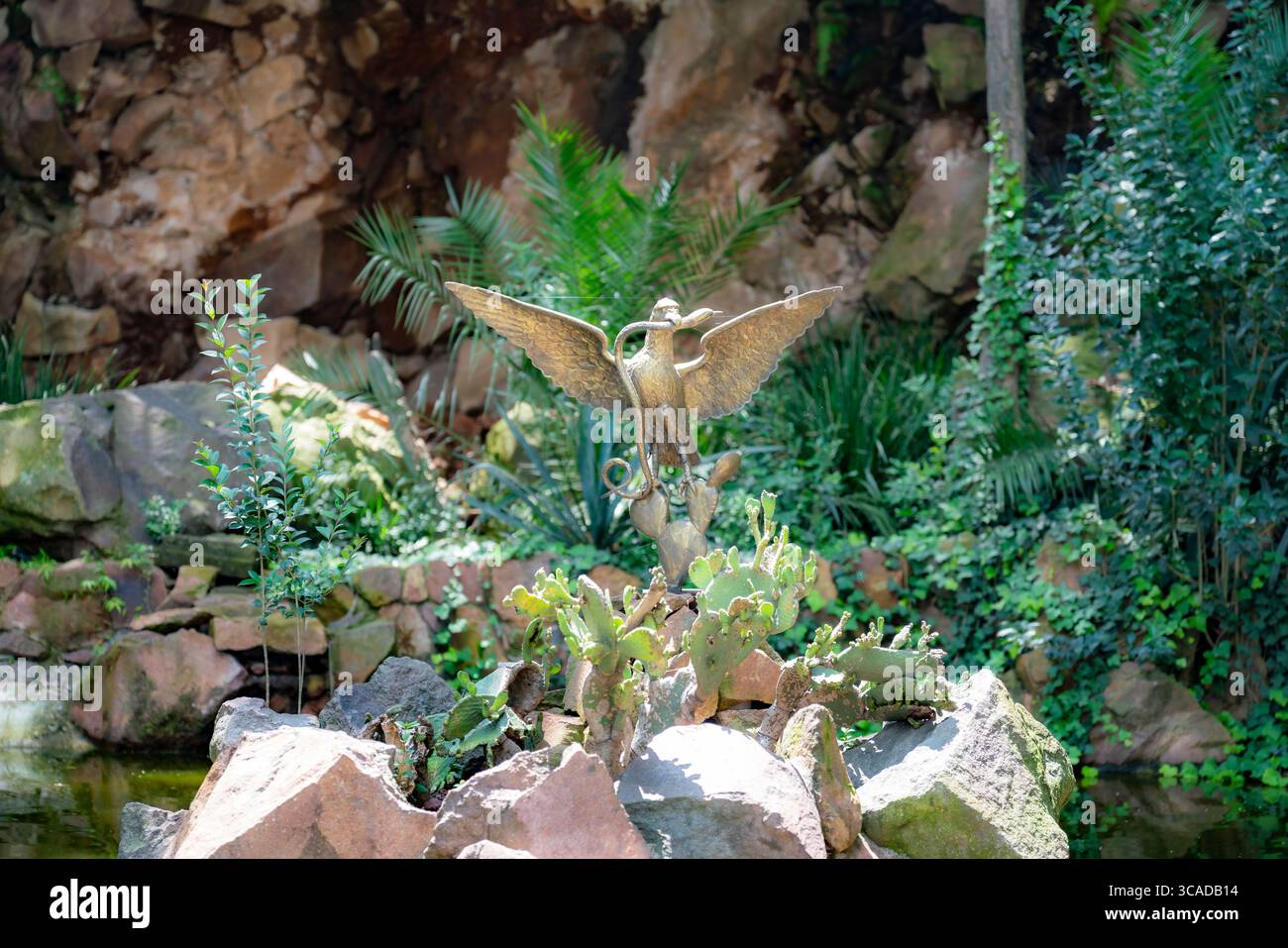 Aigle en bronze symbolique mangeant un serpent debout sur un cactus, situé sur le sentier naturel menant au château de Chapultepec, Mexico, entouré par Banque D'Images