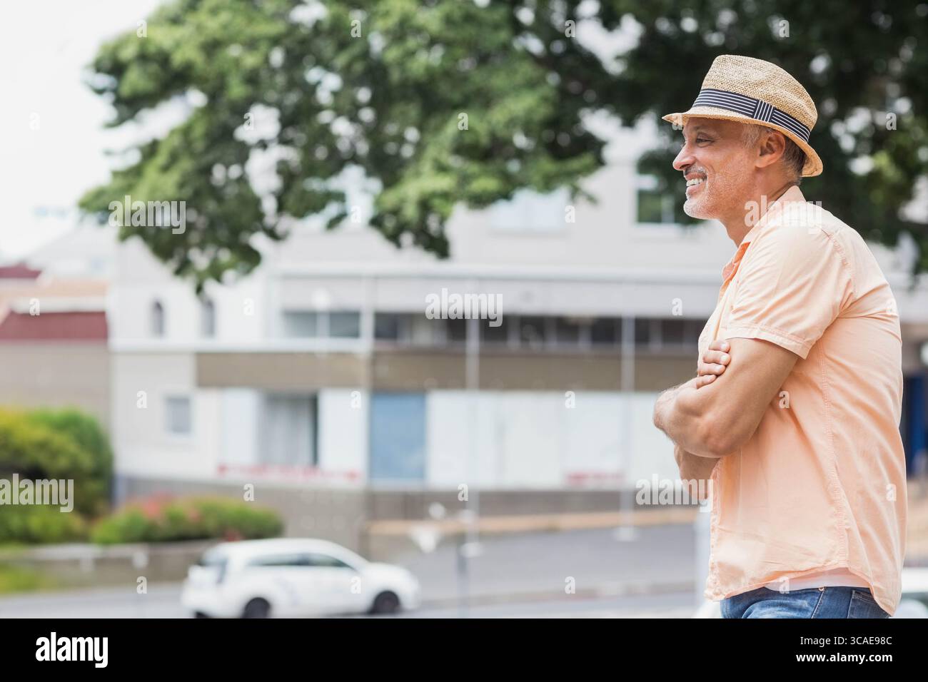 Homme d'âge moyen appuyé sur la balustrade sur le balcon de la rue tout en portant un chapeau Fedora en paille, espace de copie Banque D'Images