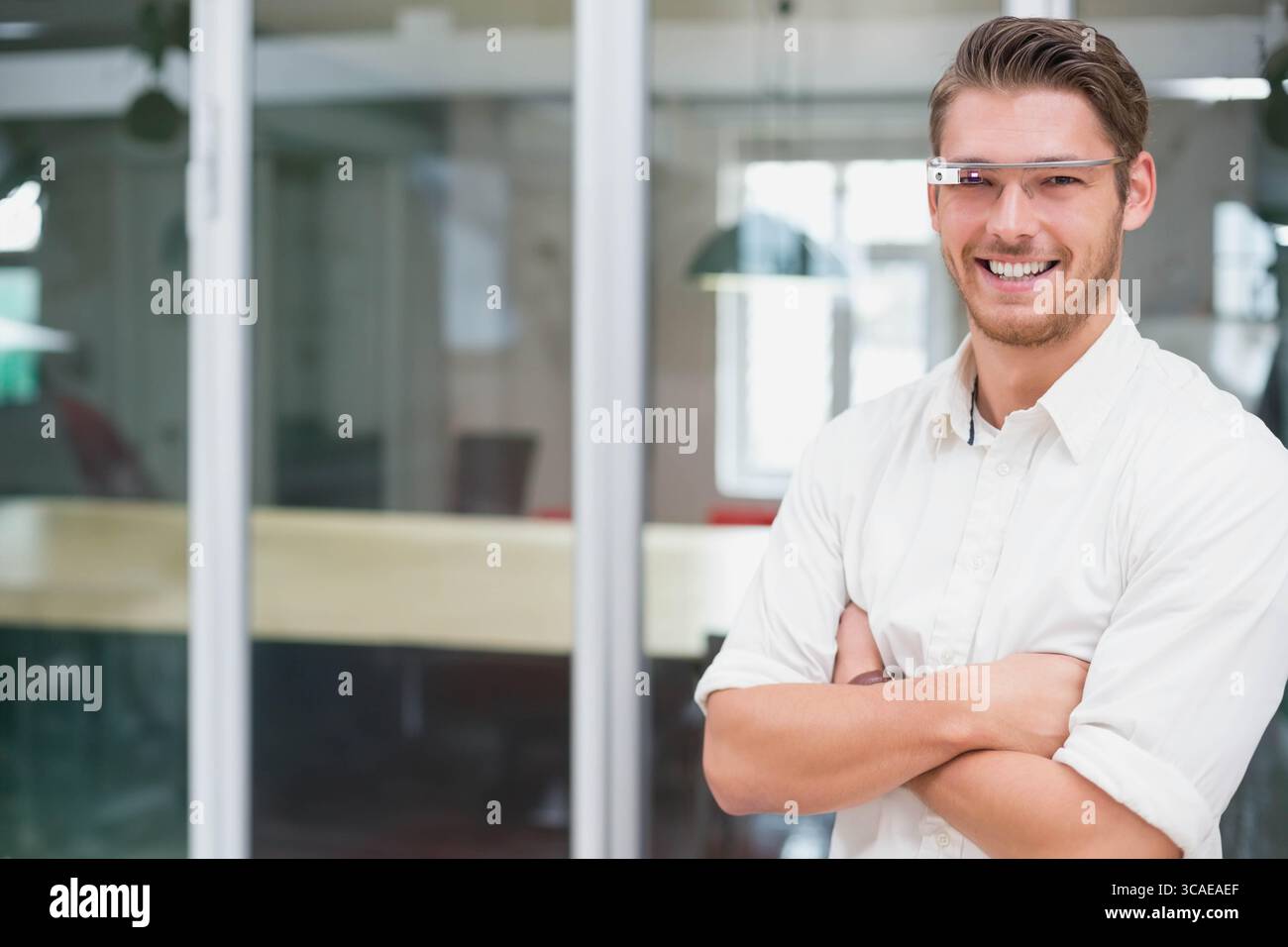 Homme portant des lunettes intelligentes et chemise debout dans le bureau à côté de la cloison en verre et de la table, copiez l'espace Banque D'Images