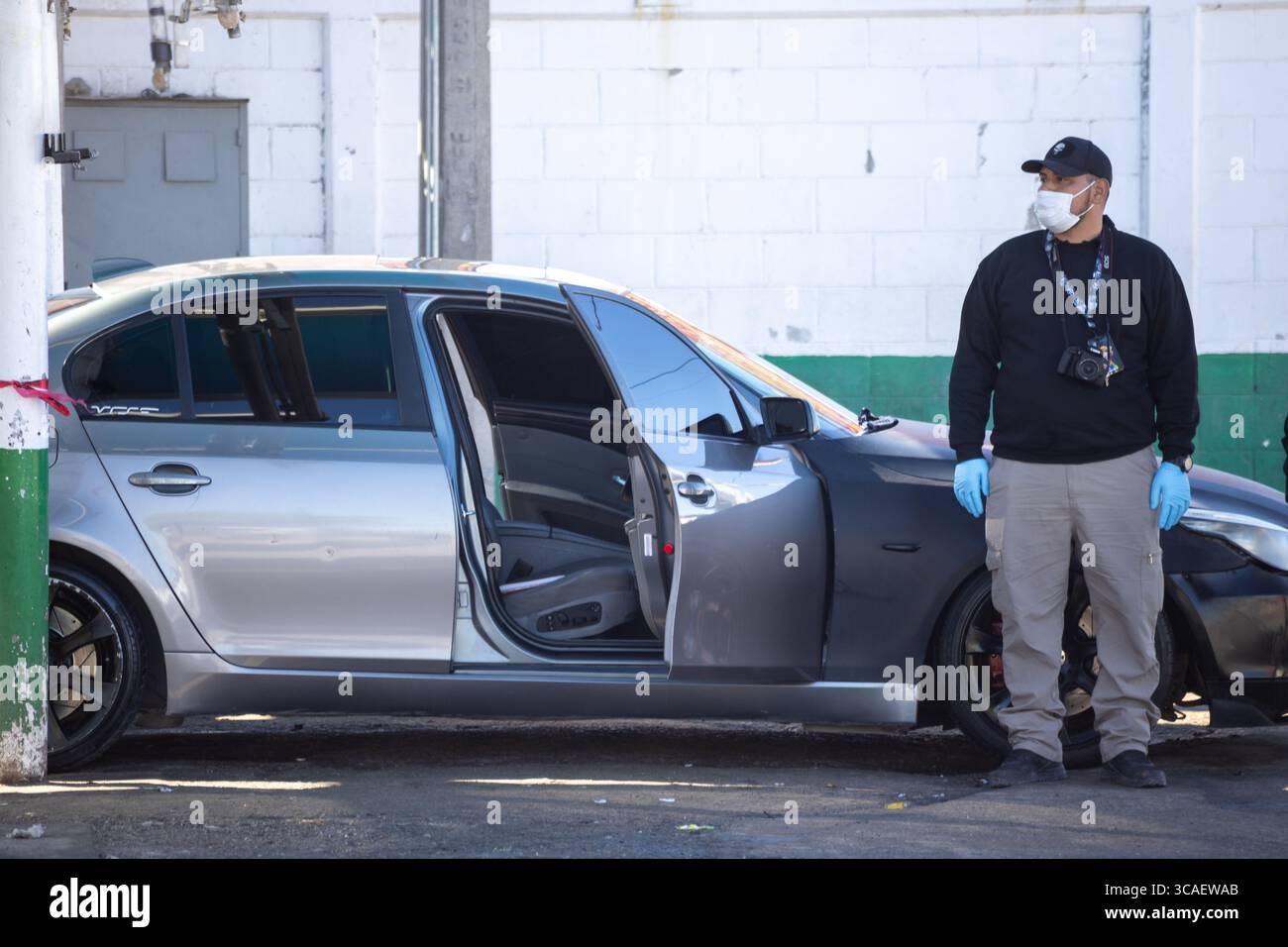 Homme en masque et gants en voiture, vigilant au milieu des luttes urbaines de Ciudad Juarez. Banque D'Images