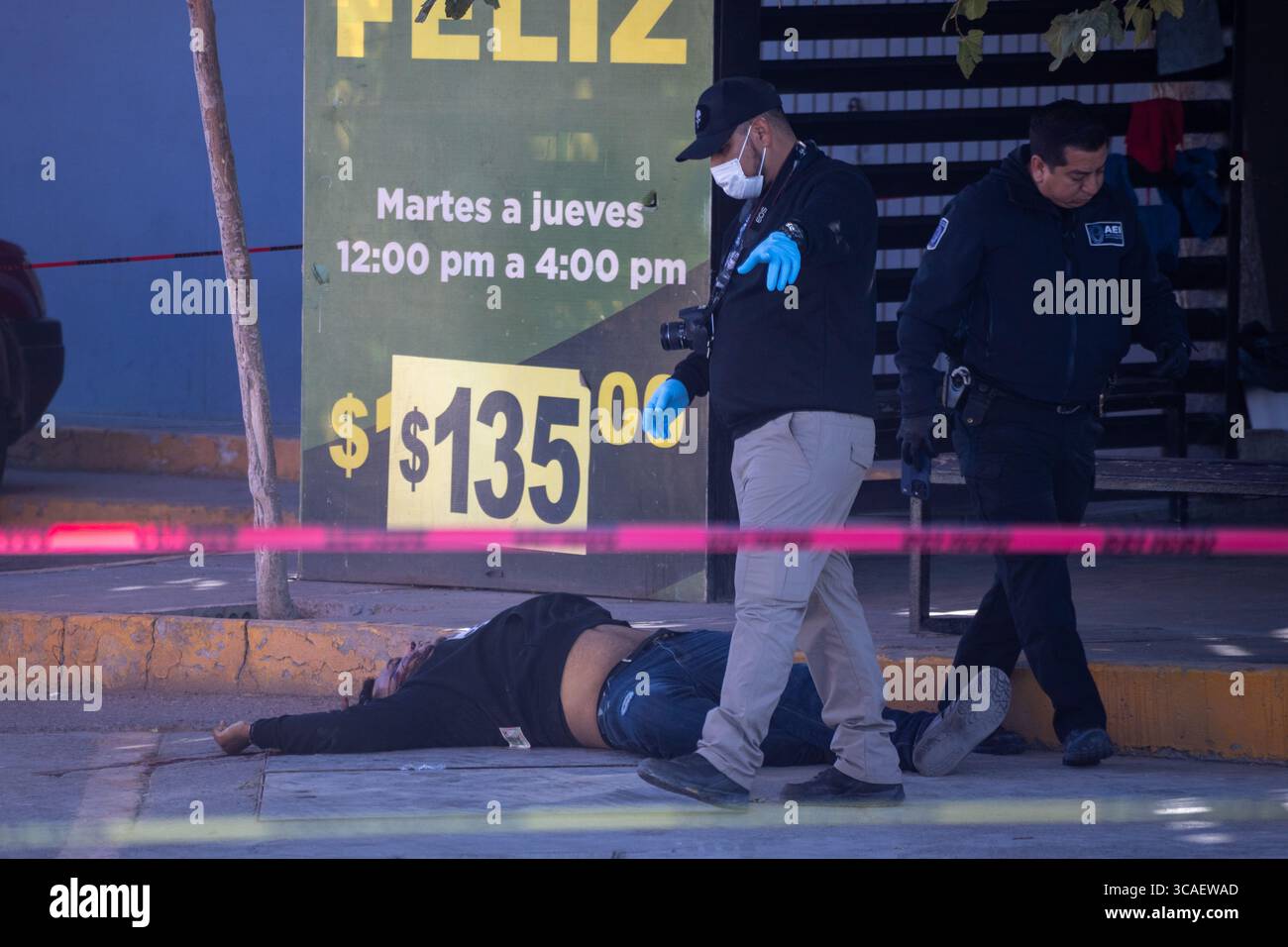 Les forces de l'ordre examinent une scène de crime avec une victime à Ciudad Juarez, mettant en lumière la violence urbaine en cours. Banque D'Images