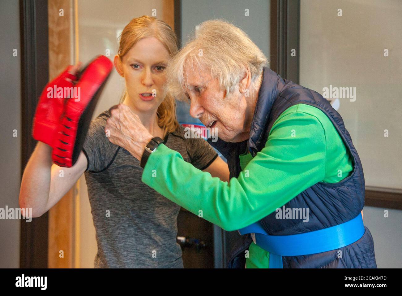 19 juillet 2017 : une femme enthousiaste de 87 ans pratique des coups de poing avec un instructeur tenant un gant d'entraînement dans un gymnase du centre senior à Huntington Beach, CA. (Crédit image : © Spencer Grant/ZUMA Press Wire) Banque D'Images