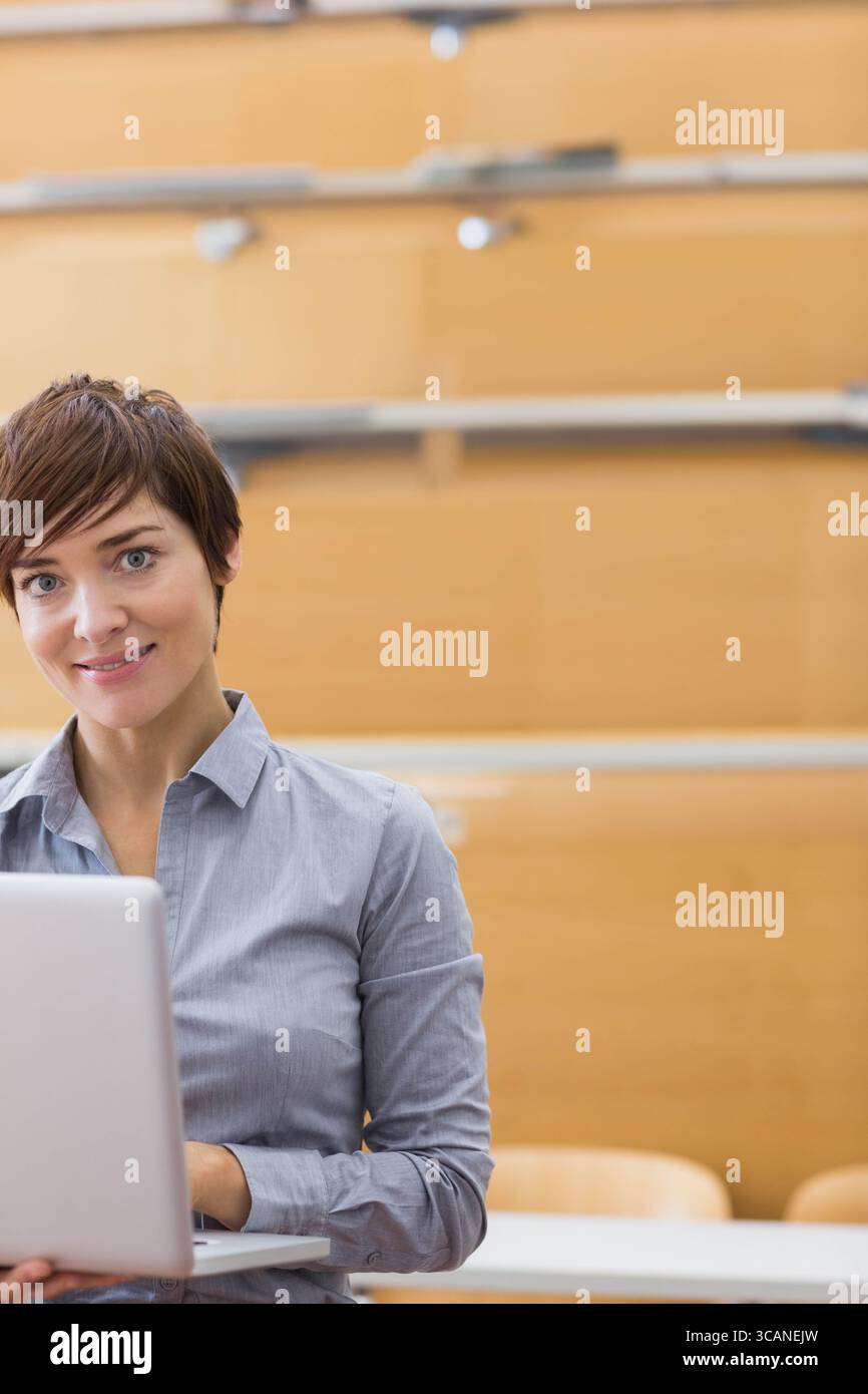 Femme travaillant sur ordinateur portable au bureau dans la salle de conférence avec des bancs et des rampes en bois, espace de copie Banque D'Images