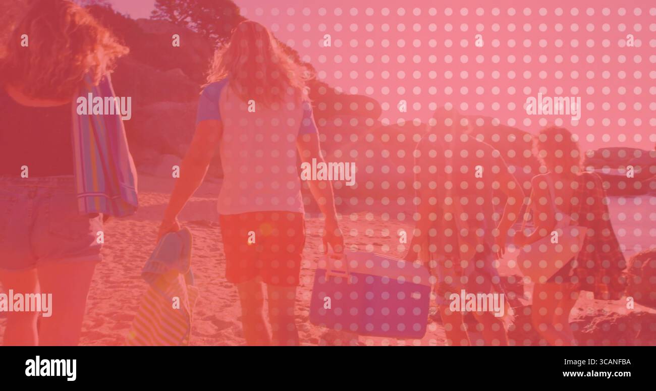 Marcher cinq amis portant du matériel de plage le long du rivage de sable près des falaises, avec glacière portable bleue Banque D'Images