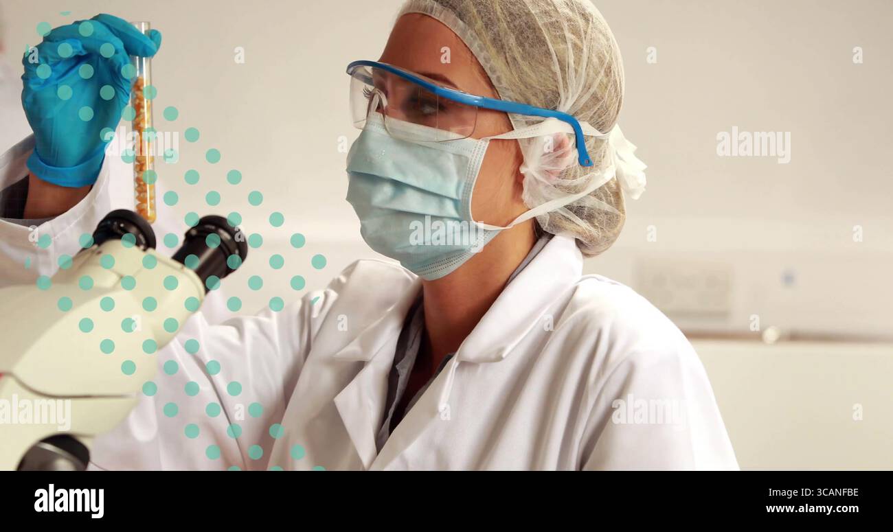 Examinateur scientifique tenant le tube d'échantillon dans la main gantée à hauteur des yeux sur la paillasse de laboratoire, avec microscope Banque D'Images