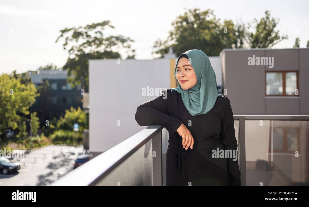 Jeune femme en hijab debout sur le balcon Banque D'Images