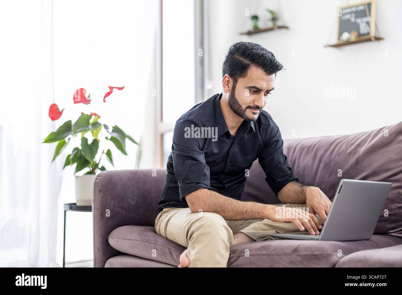 Homme utilisant un ordinateur portable tout en étant assis sur un canapé à la maison Banque D'Images