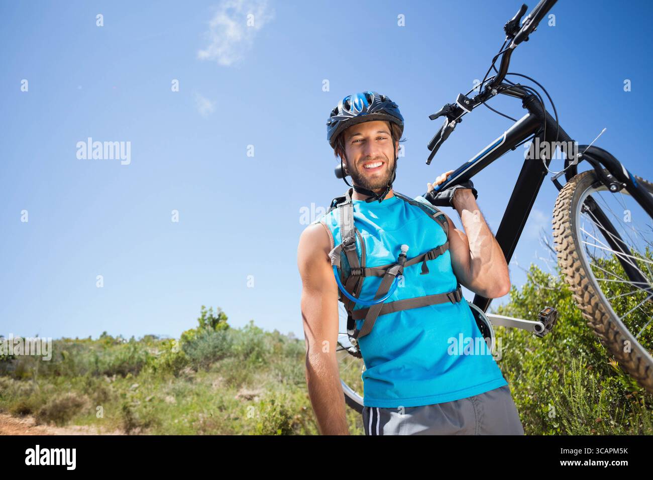 Homme debout sur le sentier portant un casque portant un vélo de montagne noir avec pack d'hydratation, espace copie Banque D'Images