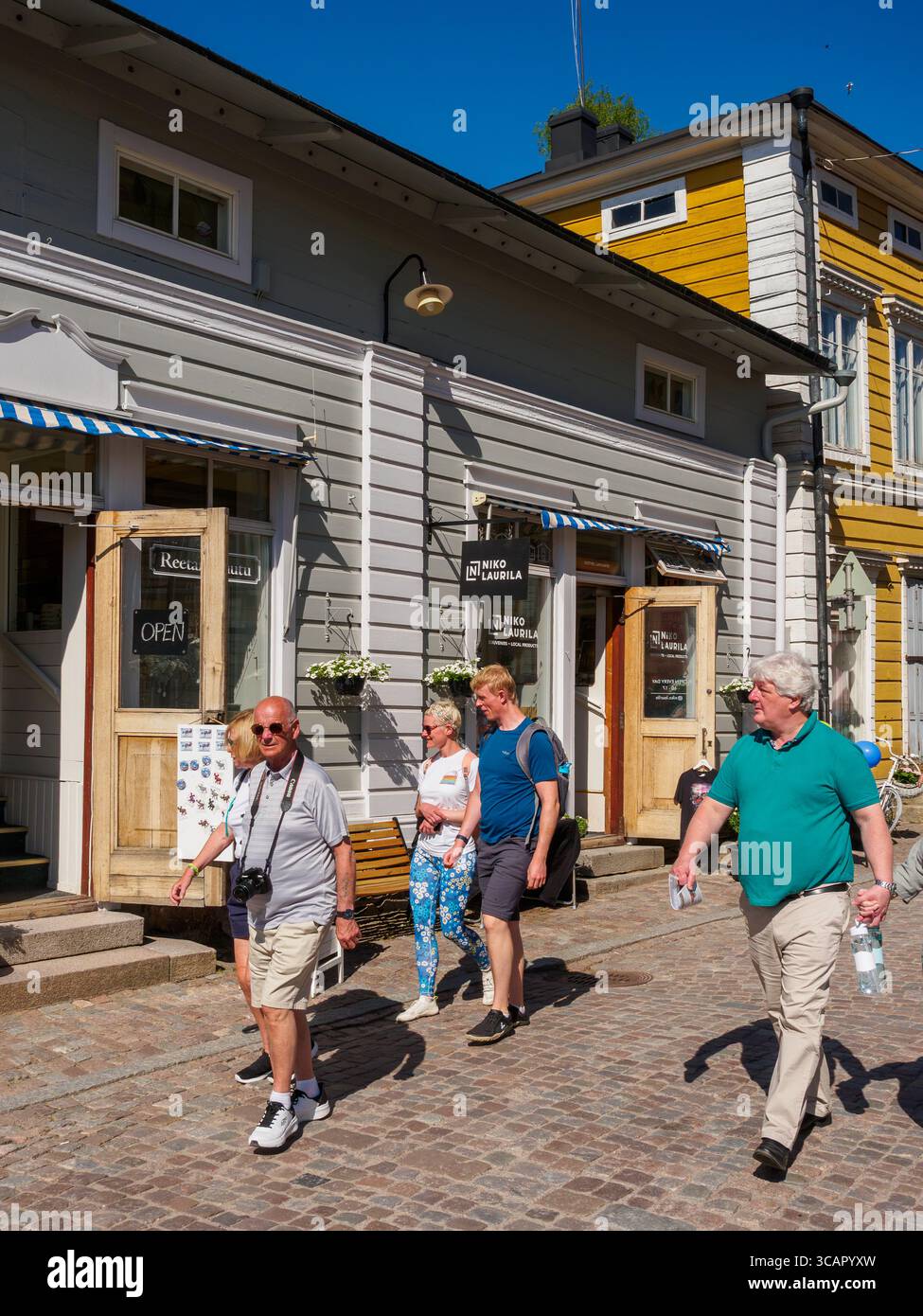 Touristes se promenant devant un magasin traditionnel en bois dans la ville médiévale finlandaise par une journée ensoleillée dans le Vieux Porvoo, Finlande. Banque D'Images