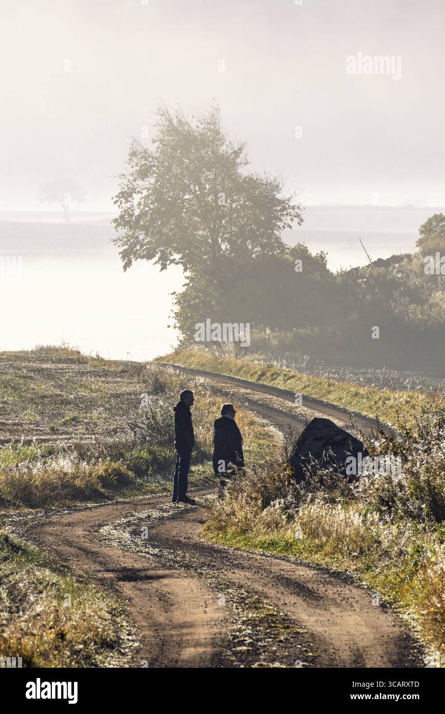 Deux personnes marchant sur une route de gravier sinueuse dans la campagne un jour d'automne brumeux Banque D'Images