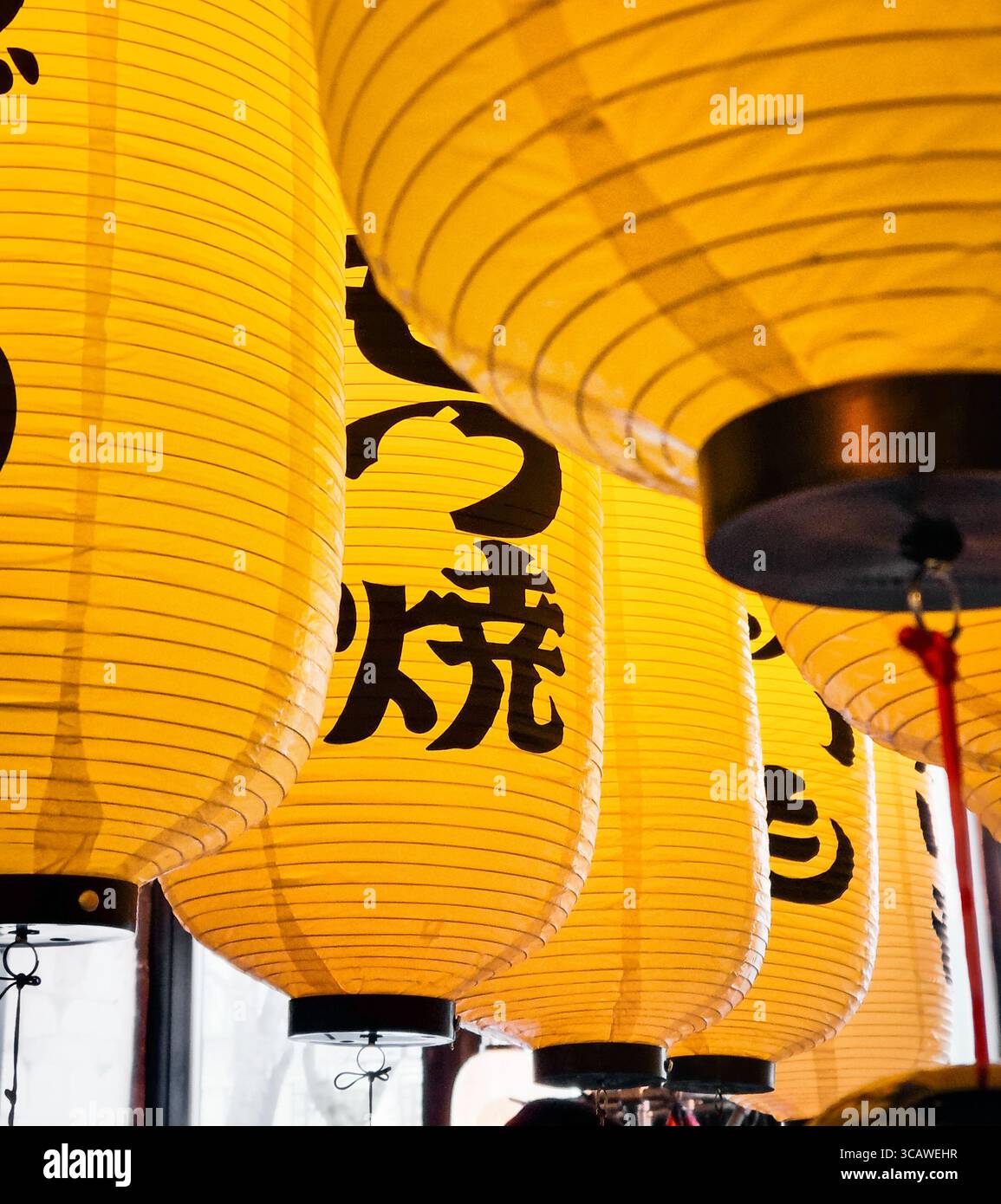Lanternes traditionnelles japonaises en papier. Rangées de lanternes en papier jaune sous le plafond dans le magasin de ramen. Banque D'Images