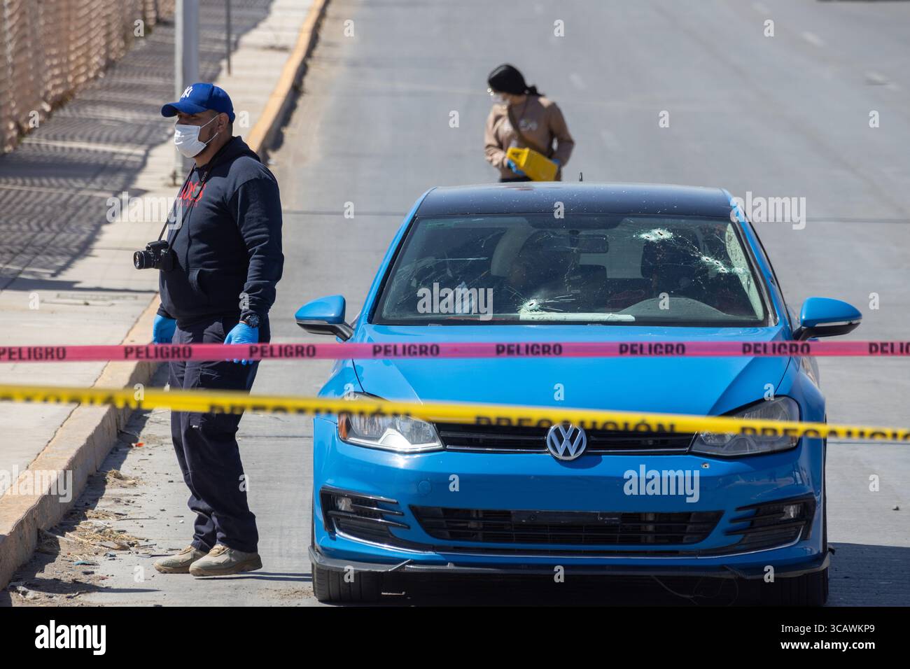 Scène de crime à Ciudad Juarez avec un homme documentant une voiture vandalisée. Banque D'Images