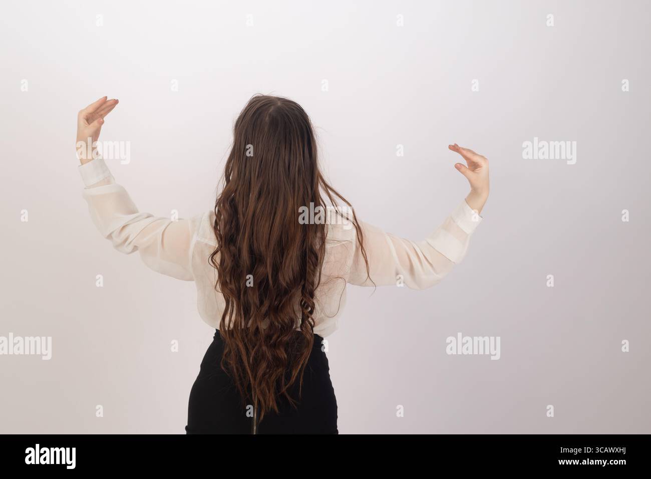 Une femme de derrière, face loin du spectateur.elle a les cheveux longs, sombres et ondulés Banque D'Images