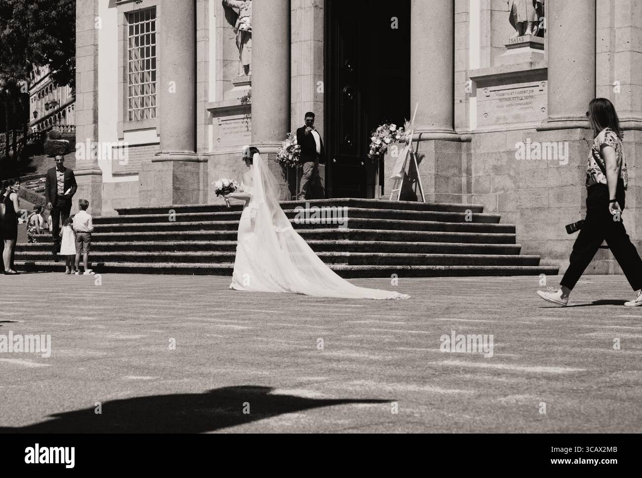 Mariée en robe coulante et voile marchant vers l'entrée de l'église Bom Jesus do Monte à Braga Banque D'Images