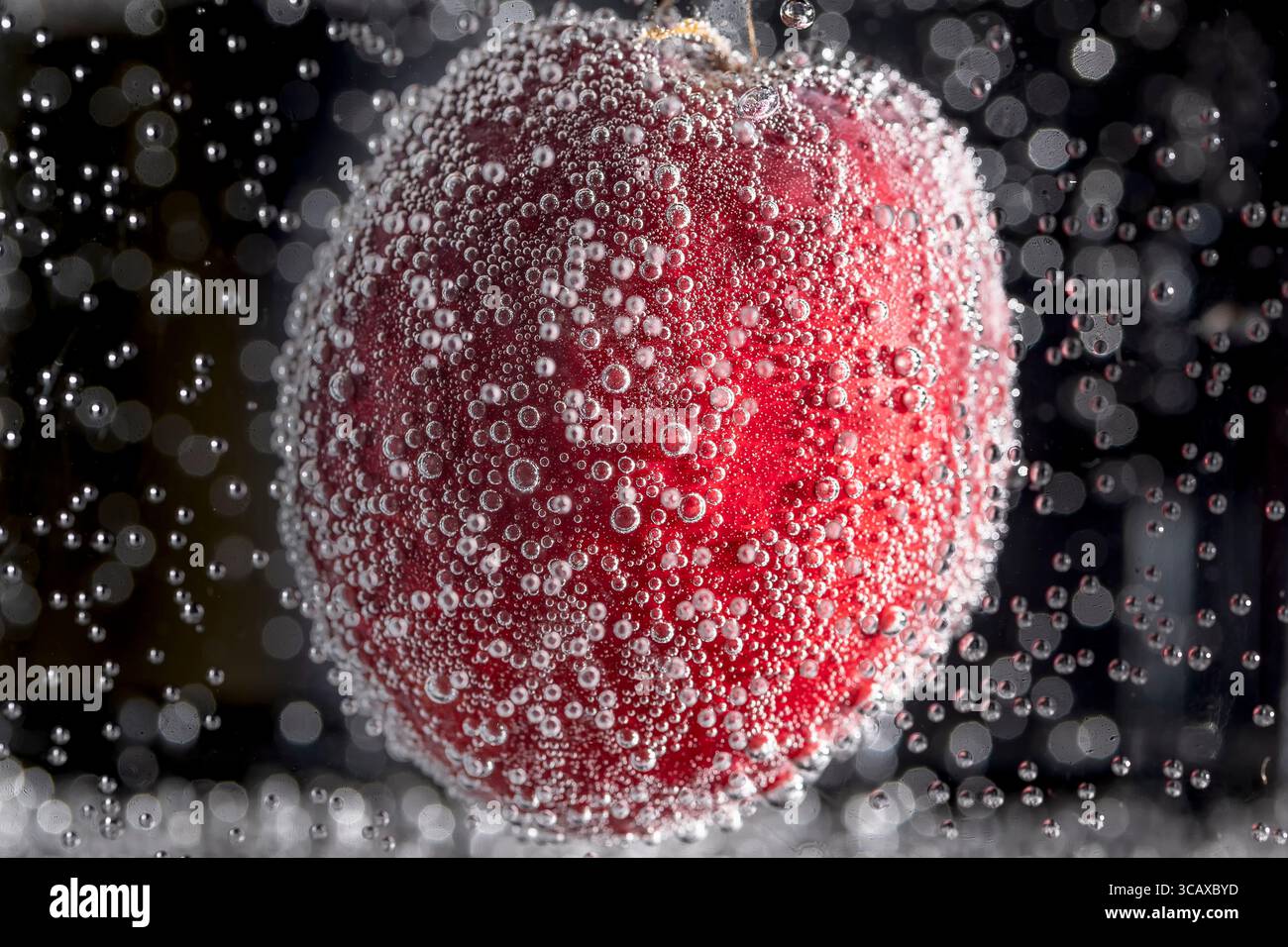 Une pêche rouge est immergée dans l'eau et recouverte de bulles d'air Banque D'Images