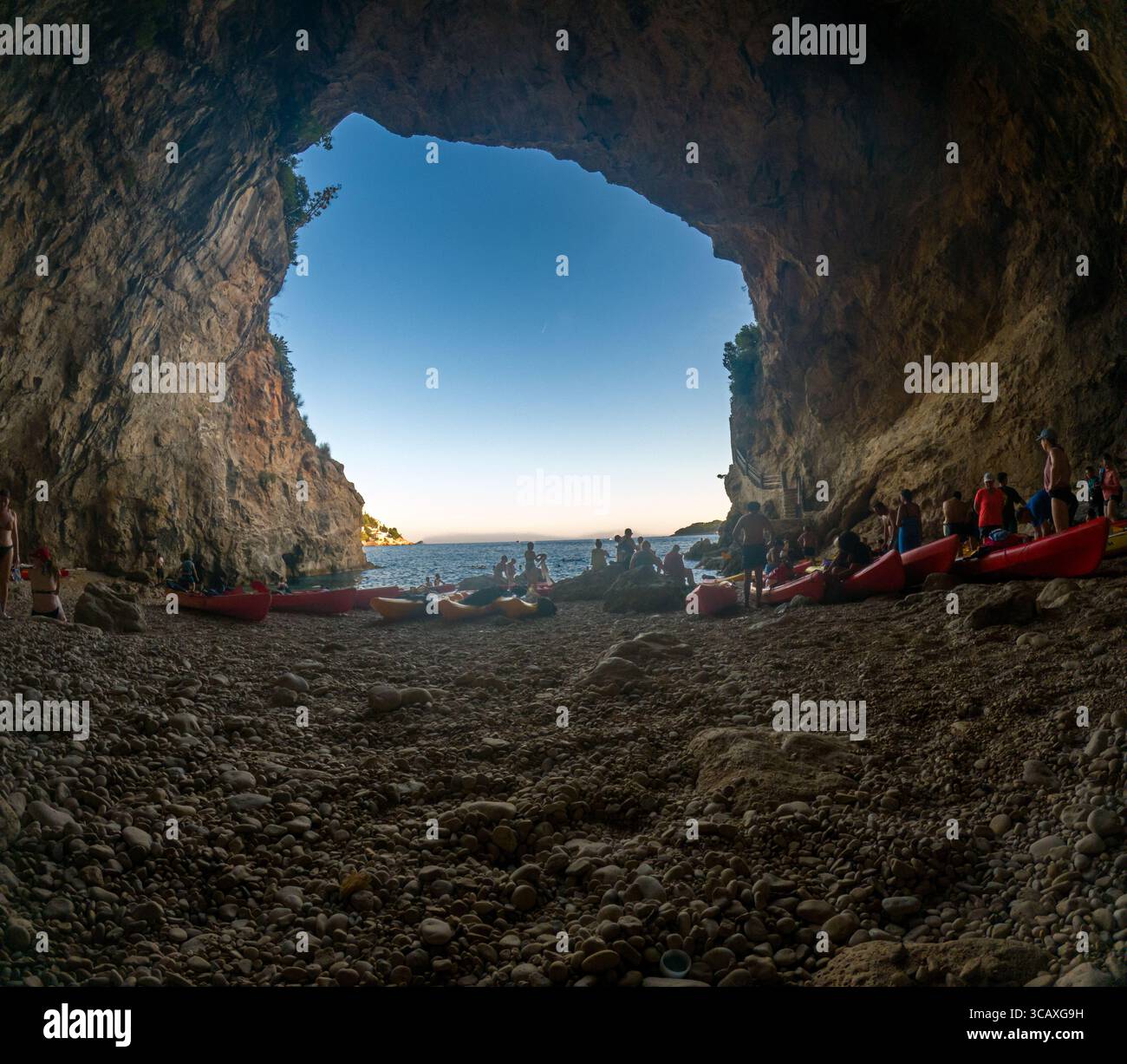 Dubrovnik, Croatie - 12 septembre 2023 : les kayakistes se rassemblent à l'intérieur d'une grotte lors d'une excursion au coucher du soleil. Les gens se reposent et profitent du paysage. Banque D'Images