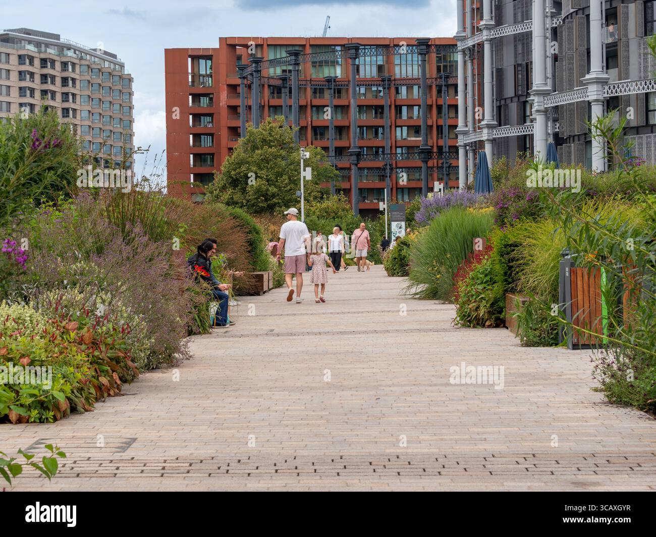Les gens marchent dans les jardins paysagers et les espaces publics du développement régénéré King's Cross un jour d'été à Londres, au Royaume-Uni. Banque D'Images