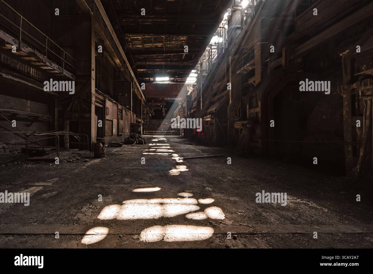 Intérieur d'usine industrielle abandonné avec des rayons de soleil spectaculaires et des machines rustiques dans un entrepôt sombre et vide Banque D'Images
