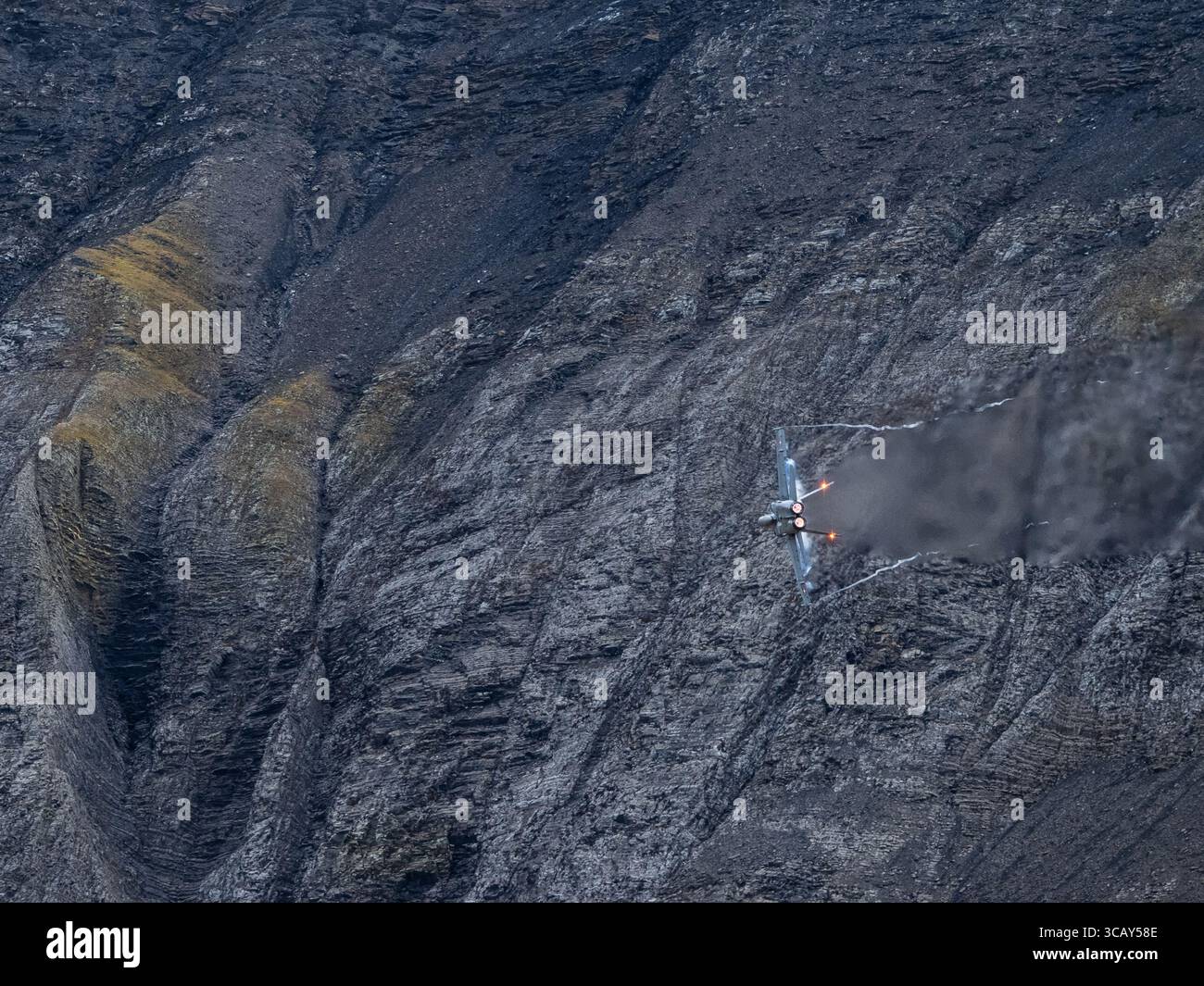 Swiss Air Force F/A-18 jet effectuant des manœuvres à grande vitesse avec post-brûleurs sur fond de montagne alpine accidentée Banque D'Images