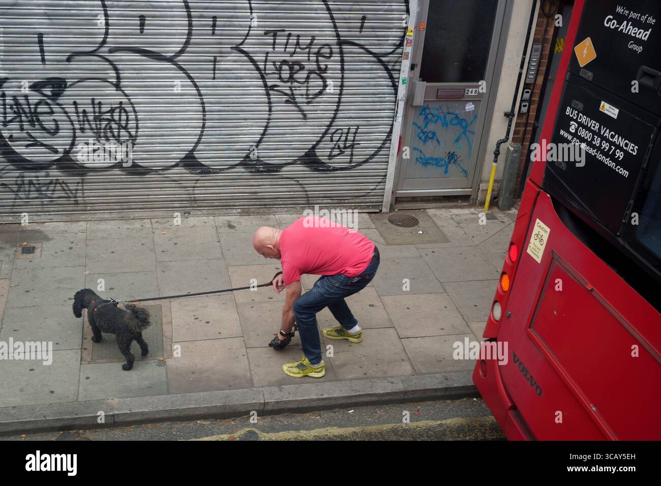 Un propriétaire d'animal de compagnie responsable ramasse le gâchis fait par son chien à Lambeth, au sud de Londres, le 7 août 2025, à Londres, en Angleterre. Banque D'Images