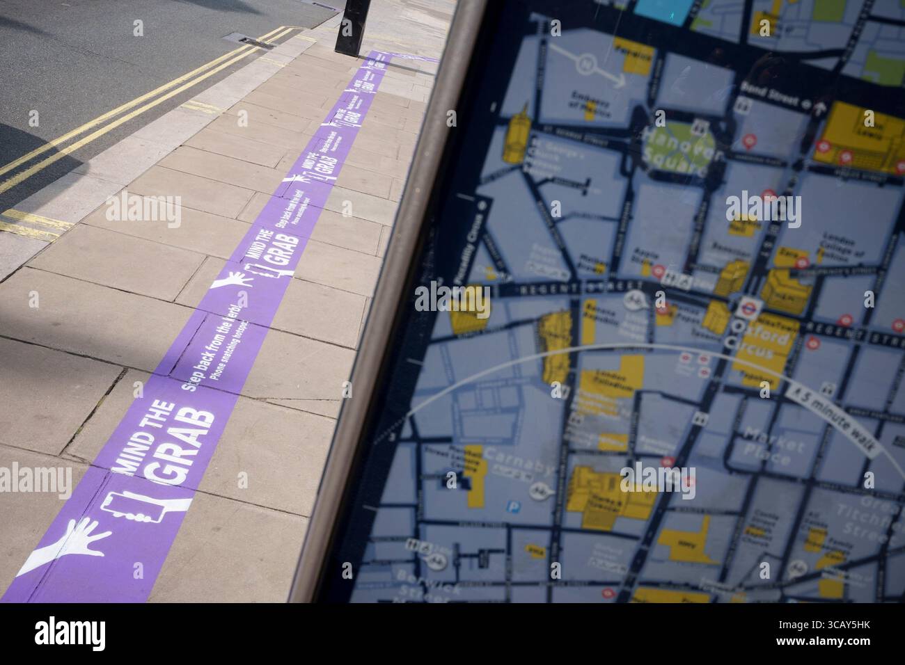 Messages sur Oxford Street qui avertissent les utilisateurs de téléphones de la tendance croissante du crime d'arrachement de téléphone, l'initiative « Mind the Grab » par Westminster, la police met et le détaillant Currys, le 7 août 2025, à Londres, en Angleterre. Les statistiques révèlent qu'en 2024, un téléphone a été volé toutes les 15 minutes à Westminster - 94 par jour et plus de 34 000 au total. Typiquement, ces vols impliquent des criminels sur des cyclomoteurs ou des vélos électriques arrachant des téléphones directement des mains des gens sur des trottoirs fréquentés. Banque D'Images