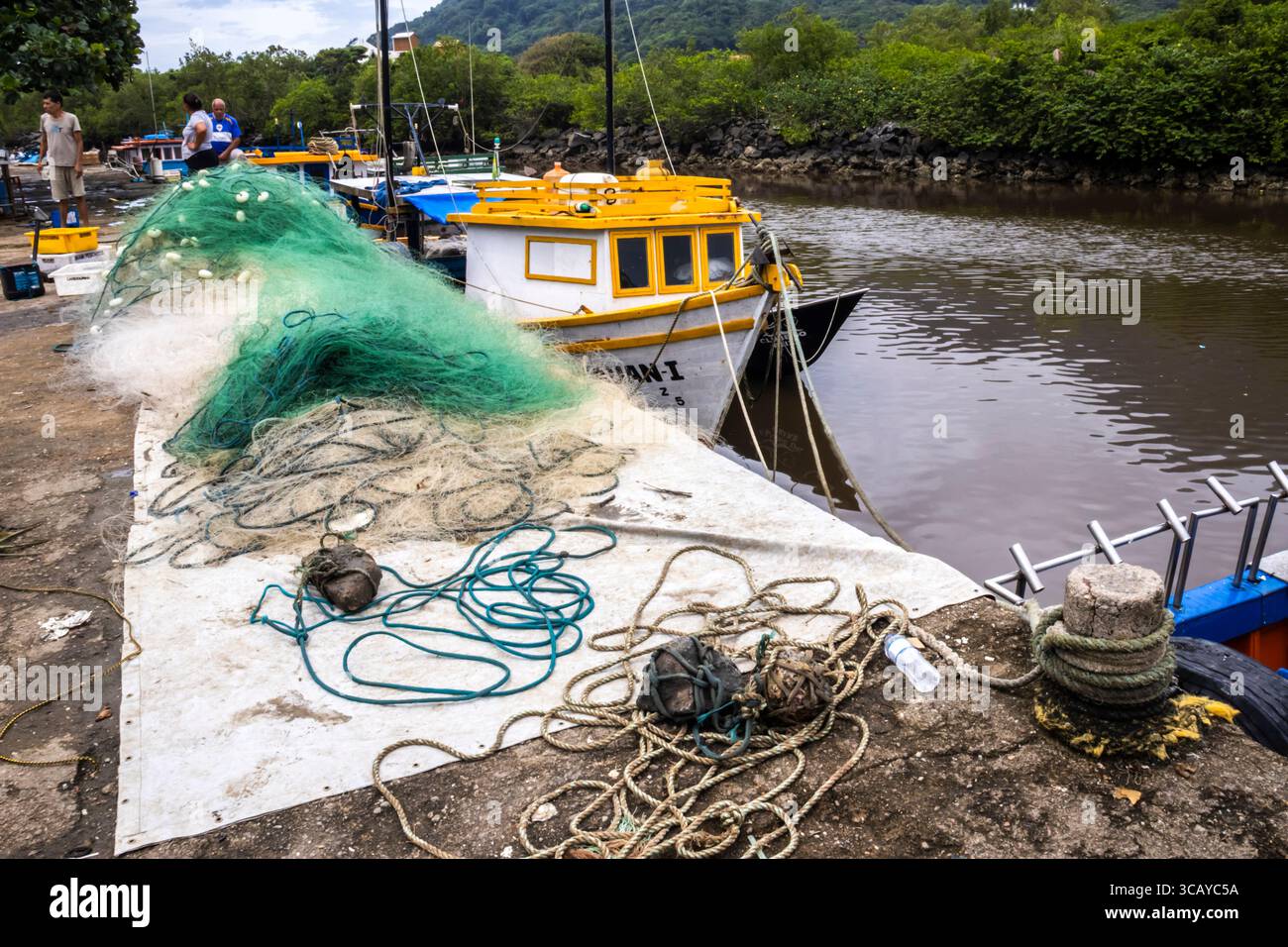 Peruibe, Sao Paulo, 17 janvier 2025. Scène de port de pêche à Peruíbe, état de Sao Paulo. Les filets colorés, les bateaux et la toile de fond de la forêt atlantique capturent t Banque D'Images