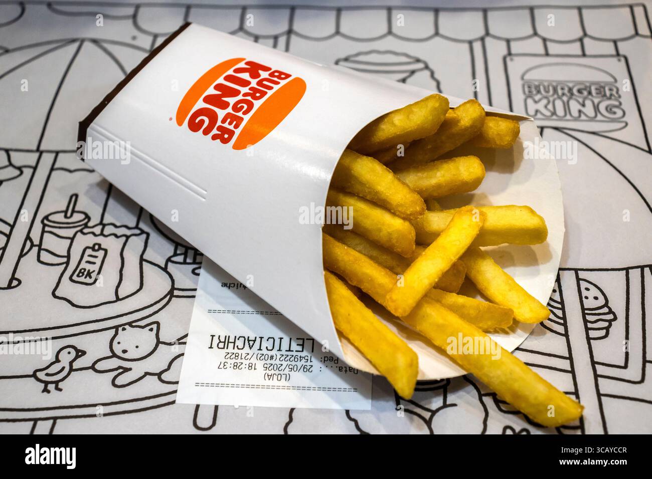 Marilia, SP, Brésil, 29 mai 2025. Frites Burger King renversées dans un sac de papier blanc sur fond de napperon illustré, mettant en valeur le son de restauration rapide Banque D'Images
