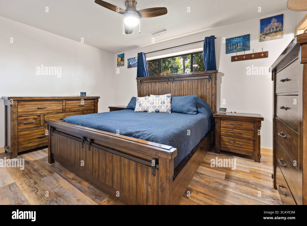 Une chambre confortable avec un lit confortable, une commode élégante, une table de chevet pratique et un ventilateur de plafond de refroidissement pour les nuits chaudes Banque D'Images