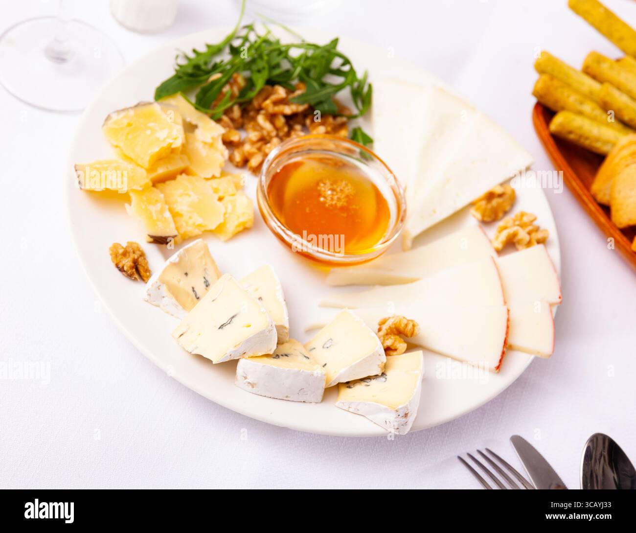Différents types de fromage tranchés et servis sur une assiette avec un bol de miel, des noix Banque D'Images