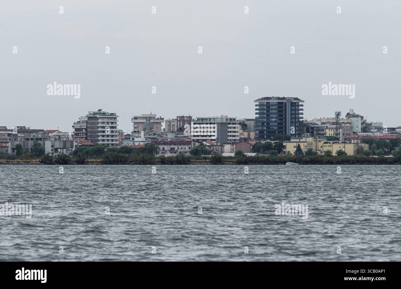 Vue panoramique de Grado depuis l'île de Barbana, avec des bâtiments modernes s'élevant au-dessus de la lagune par temps nuageux. Banque D'Images