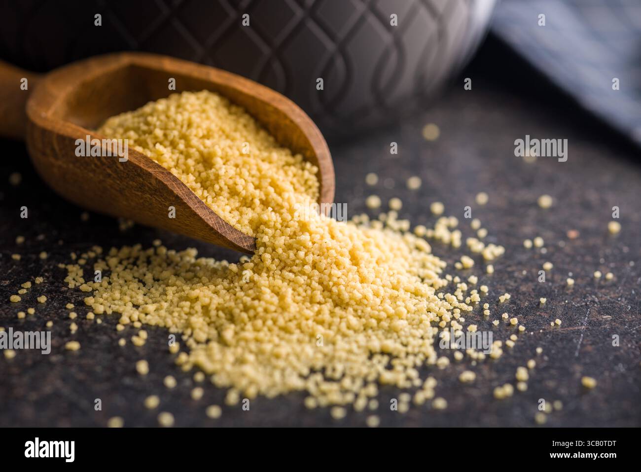 Couscous cru en cuillère sur une table noire. Banque D'Images