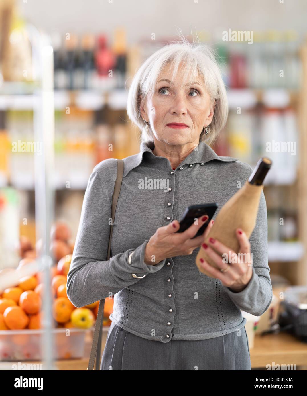 Femme âgée scannant le code qr du vin Banque D'Images