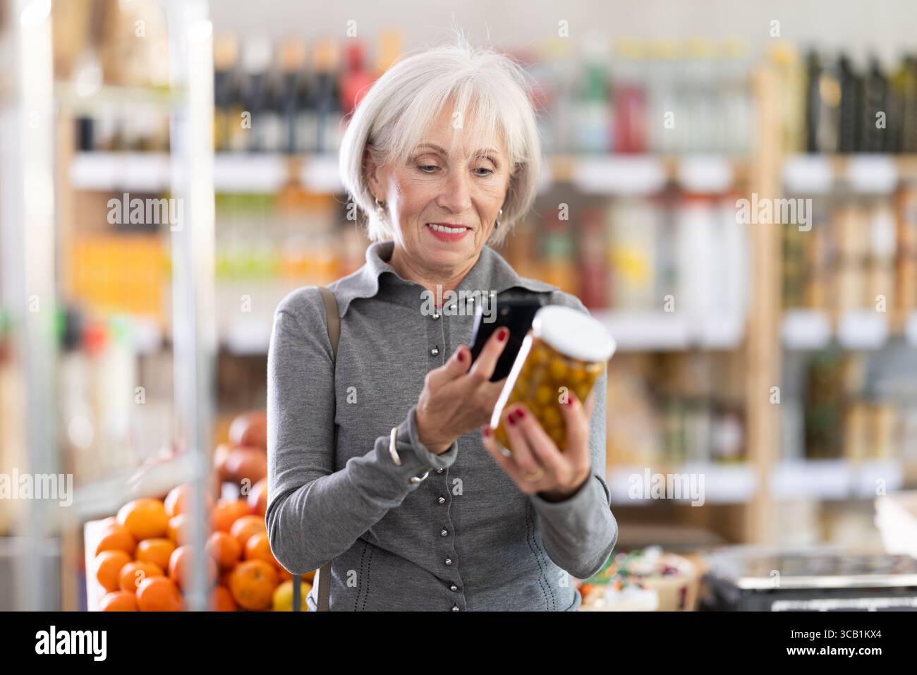 Femme âgée scannant le code qr pour les olives Banque D'Images