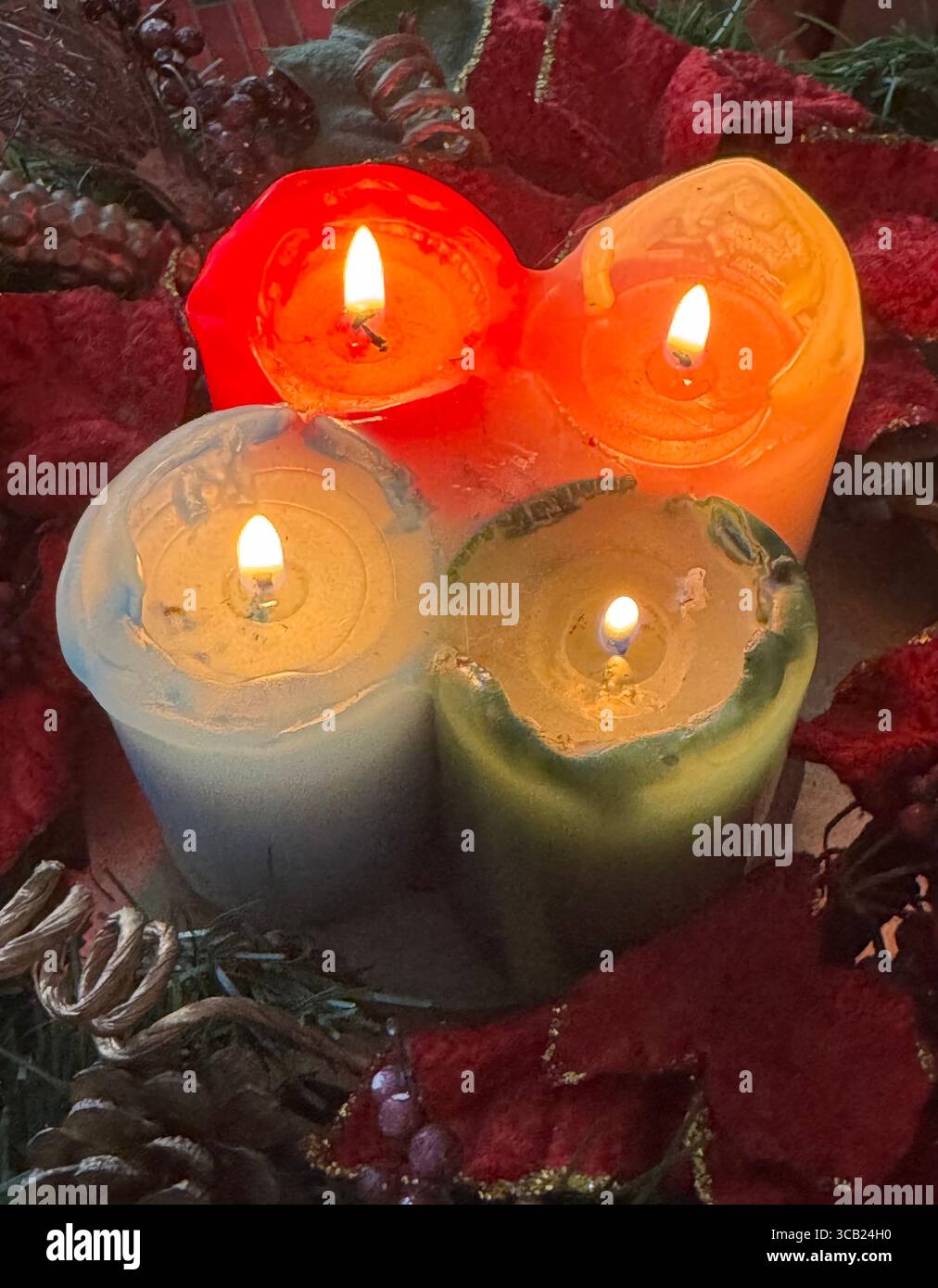 Quatre bougies colorées allumées dans les tons rouge, orange, bleu et vert, créant une ambiance chaleureuse et confortable. - Image de stock capturée avec un smartphone
