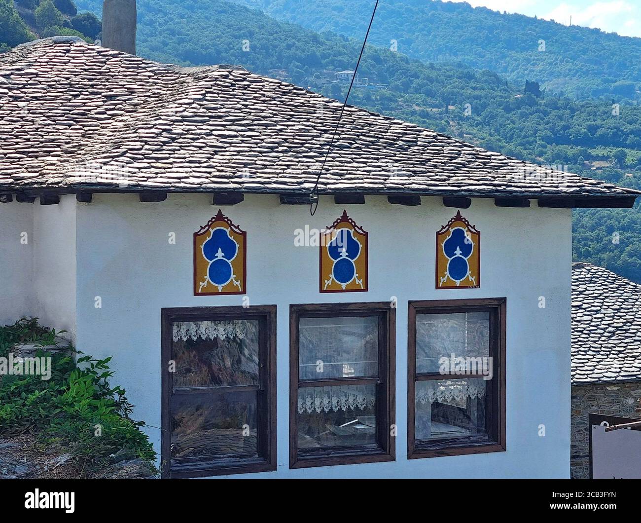 Maison traditionnelle peinte en blanc avec toit en tuiles grises et décoration dans le village-réserve historique de Makrinitsa, en Grèce Banque D'Images