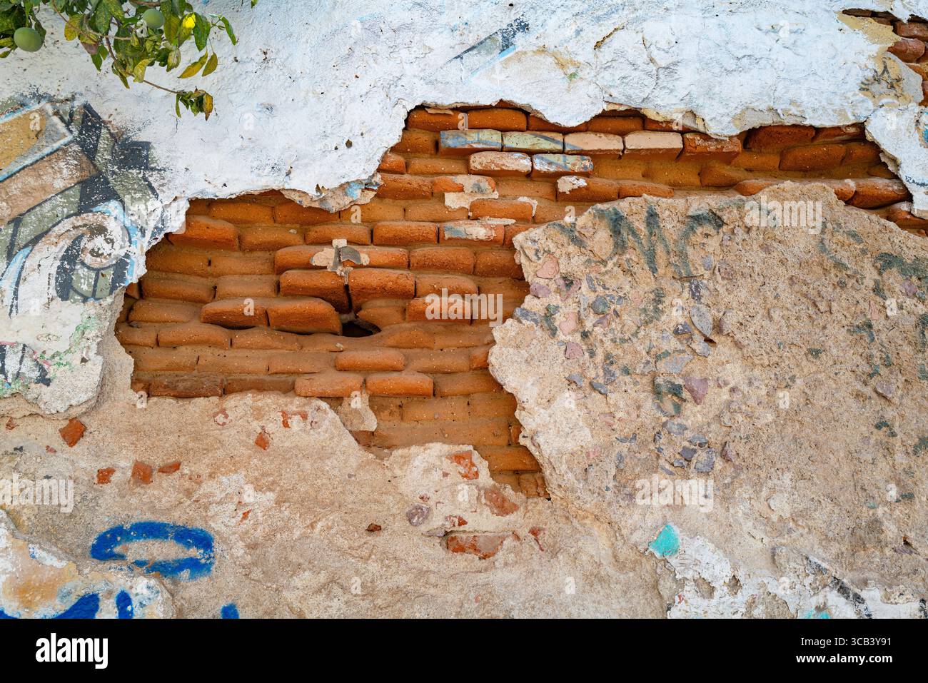 Brique rouge tirée exposée avec stuc brisé sur le mur d'un bâtiment dans le quartier du centre-ville de la Paz, BCS Mexique. Banque D'Images
