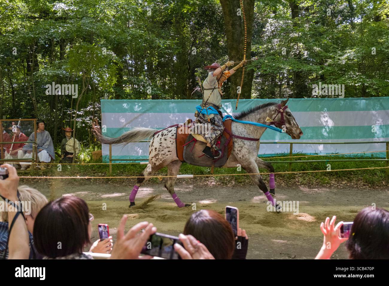 Scène dynamique du tir à l'arc traditionnel japonais pendant le festival Yabusame Shinji, regardé par un public engagé. Forêt de Tadasu-no-Mori, Kyoto Banque D'Images