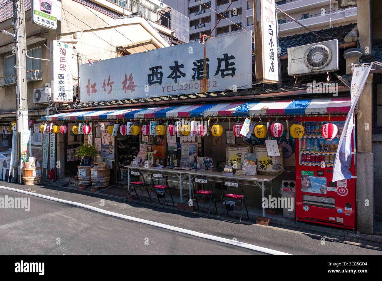 Shochikubai Nishimoto Liquor Store dans un environnement urbain, orné de lanternes suspendues colorées et d'une signalisation vibrante, mettant en valeur le charme culturel et Banque D'Images