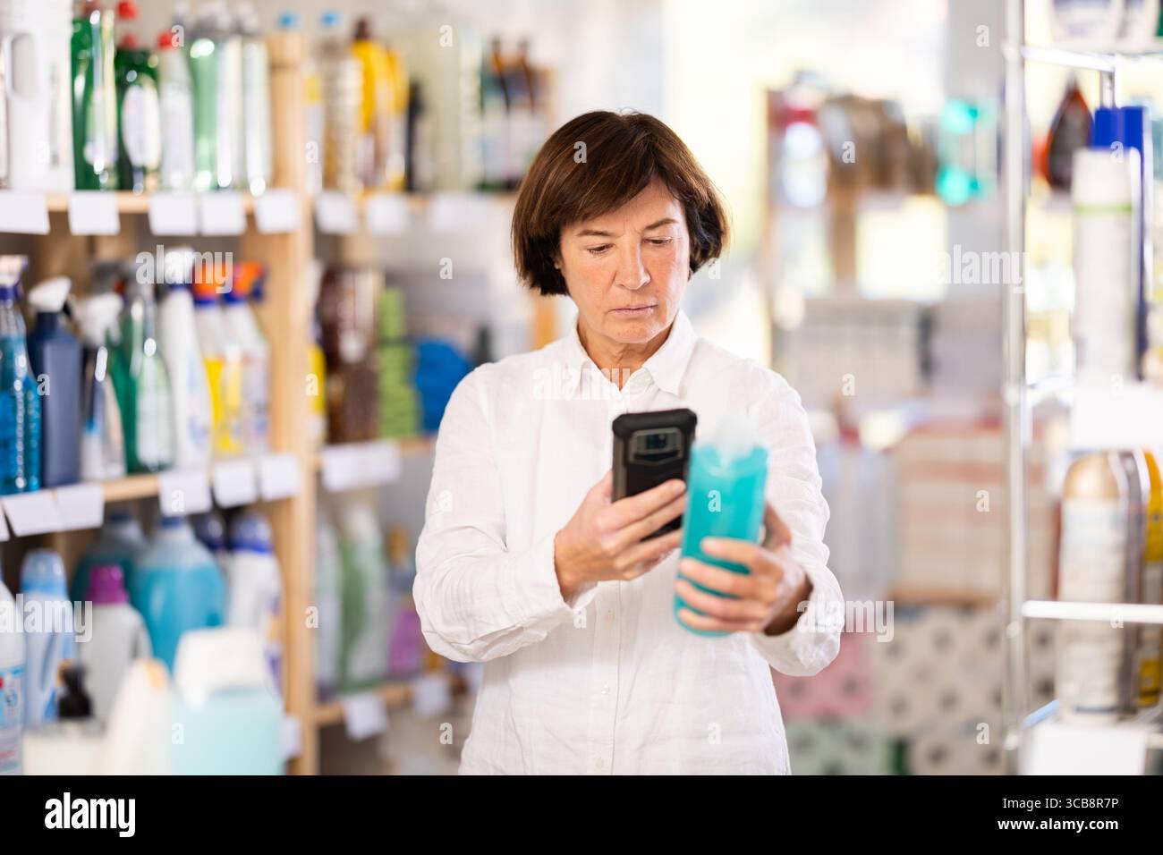 Femme âgée scannant le code qr pour shampooing ou gel douche Banque D'Images