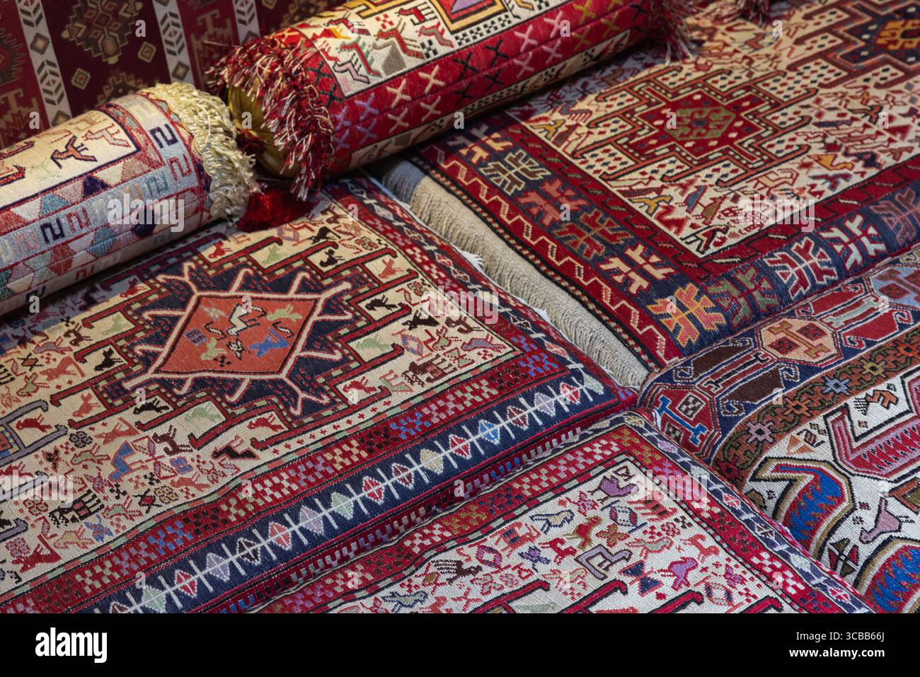 Tapis et coussins aux motifs vifs présentant un design traditionnel complexe, soigneusement disposés dans des décors lumineux et colorés englobant un ri Banque D'Images