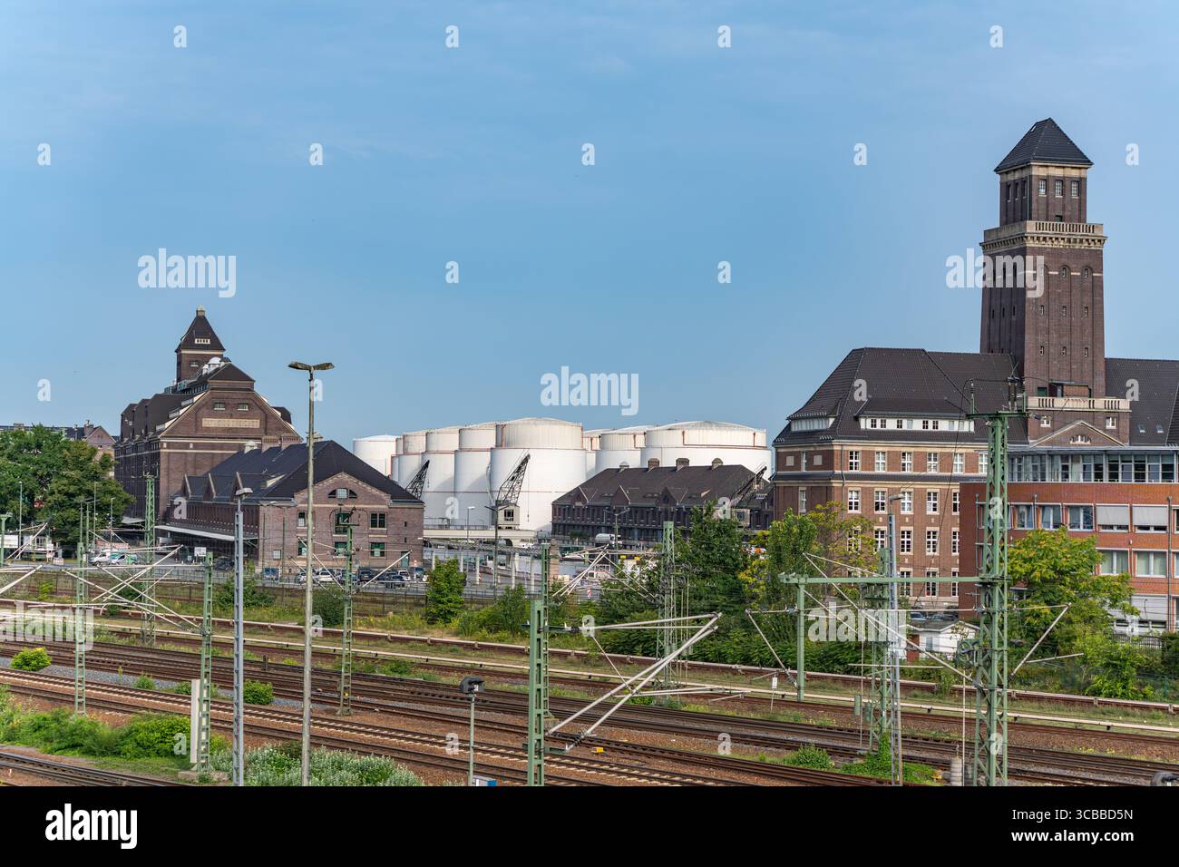 Zone portuaire industrielle avec silos. Un dépôt de fret avec des bâtiments historiques et de grands silos blancs domine la scène. Nombreuses pistes et pylônes crisscr Banque D'Images