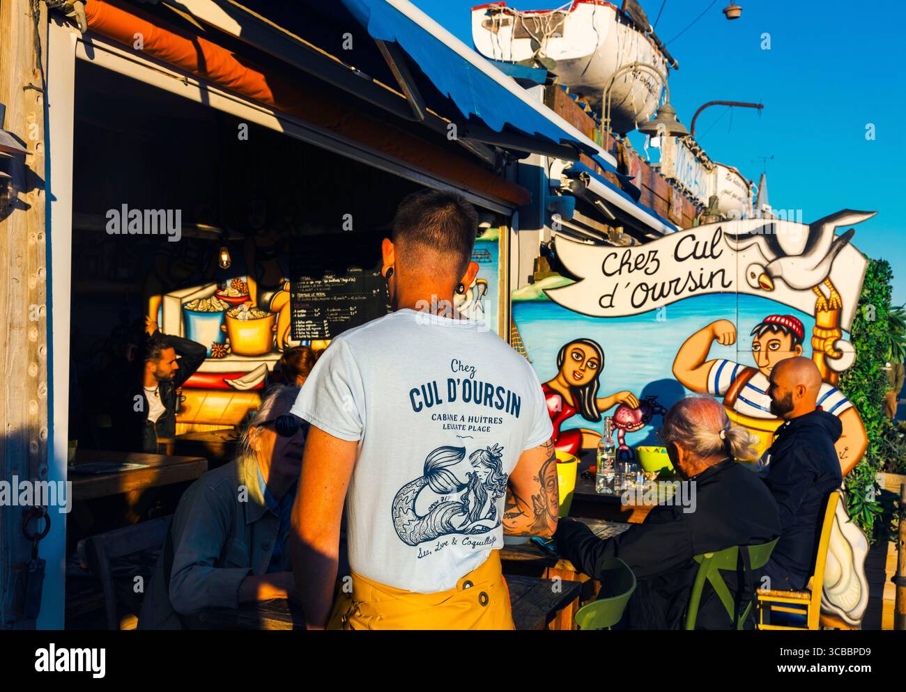 France, Aude, Parc naturel régional Narbonnaise en Méditerranée, Côte du midi, Côte du midi, Grand Narbonne, Leucate, Grau de Leucate, clients et touristes dégustant des huîtres sur la terrasse d'une cabane à huîtres en été Banque D'Images